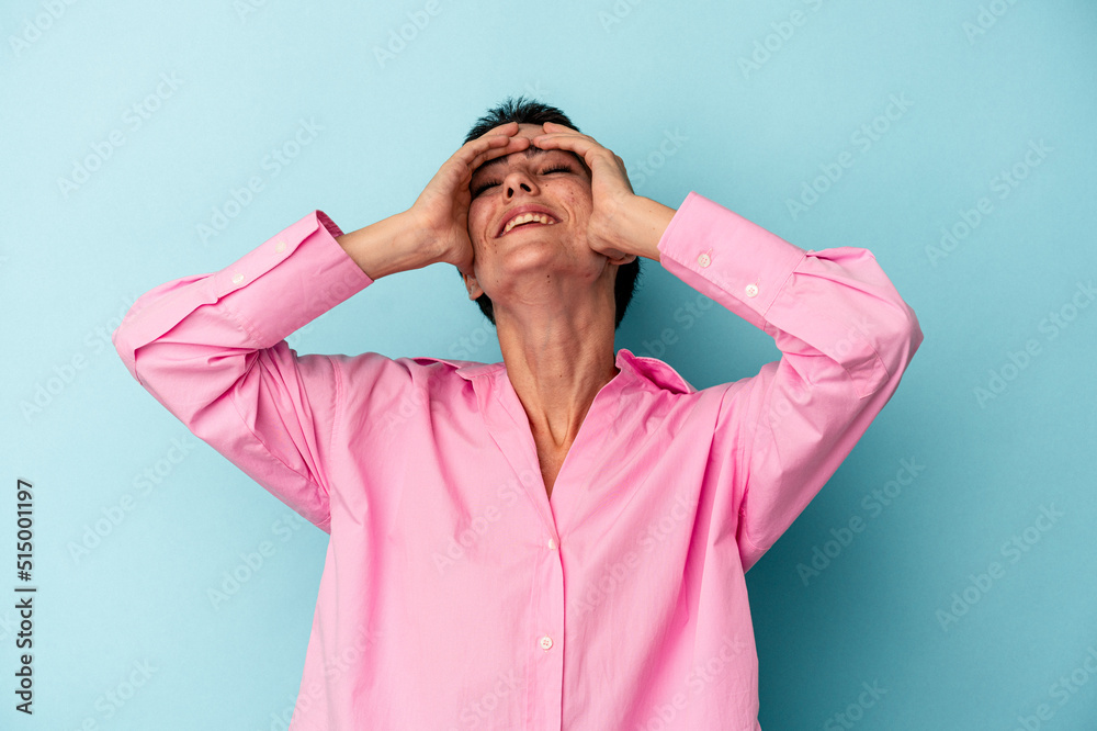 Young caucasian woman isolated on blue background laughs joyfully keeping hands on head. Happiness concept. Young caucasian woman isolated on blue background laughs joyfully keeping hands on head. Happiness concept.