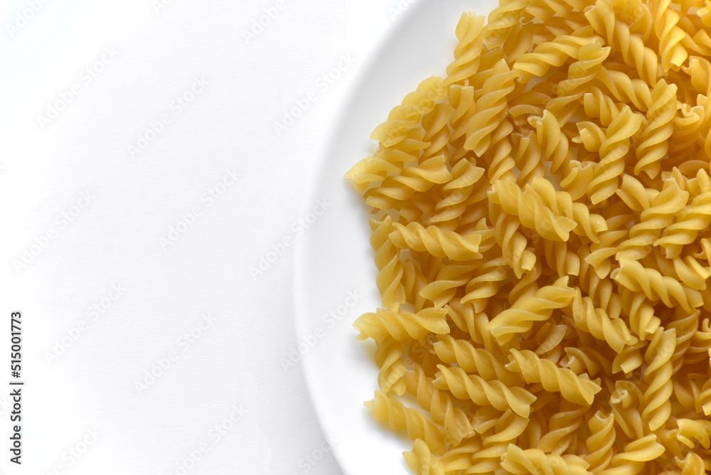Yellow twisted raw pasta on a white plate