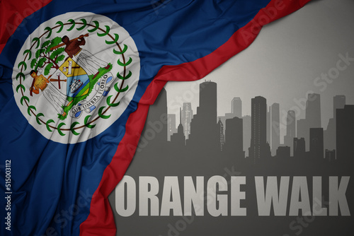 abstract silhouette of the city with text Orange Walk near waving national flag of belize on a gray background. 3D illustration