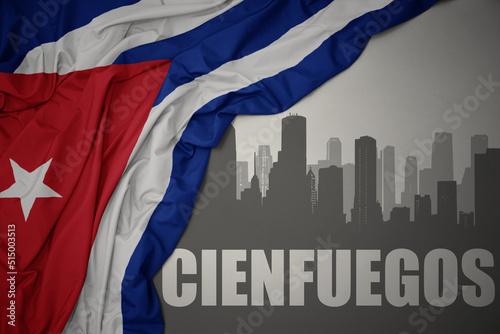 Photography abstract silhouette of the city with text Cienfuegos near waving national flag of cuba on a gray background