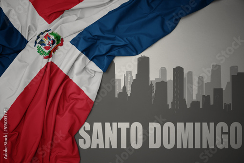 abstract silhouette of the city with text Santo Domingo near waving national flag of dominican republic on a gray background. 3D illustration photo