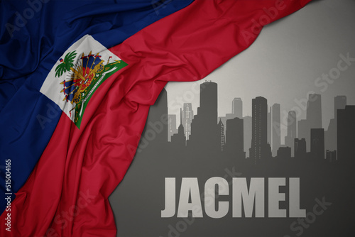 abstract silhouette of the city with text Jacmel near waving national flag of haiti on a gray background. 3D illustration