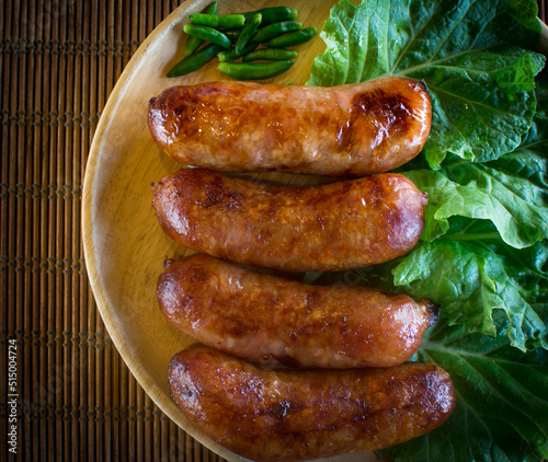 Isaan sausage or Thai Northeastern sausage , pork and rice sausages (Sai Krok Isan ) on wood plate with cabbage, and chilli