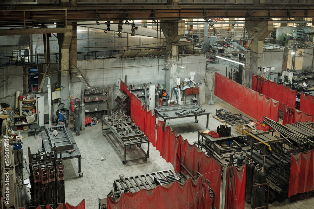 Above angle of part of spacious workshop of industrial plant or manufactory with several sections divided by red curtains