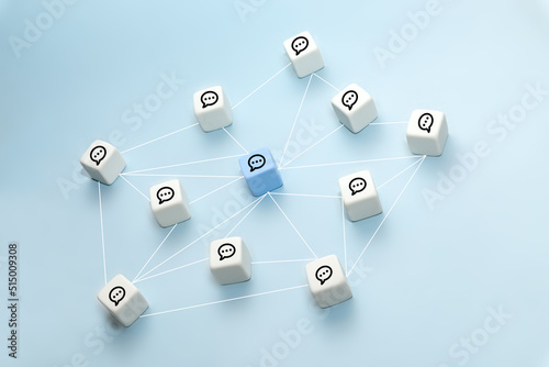 The concept of online communication or social networks. White cubes with speech bubbles connected by lines on a blue background.