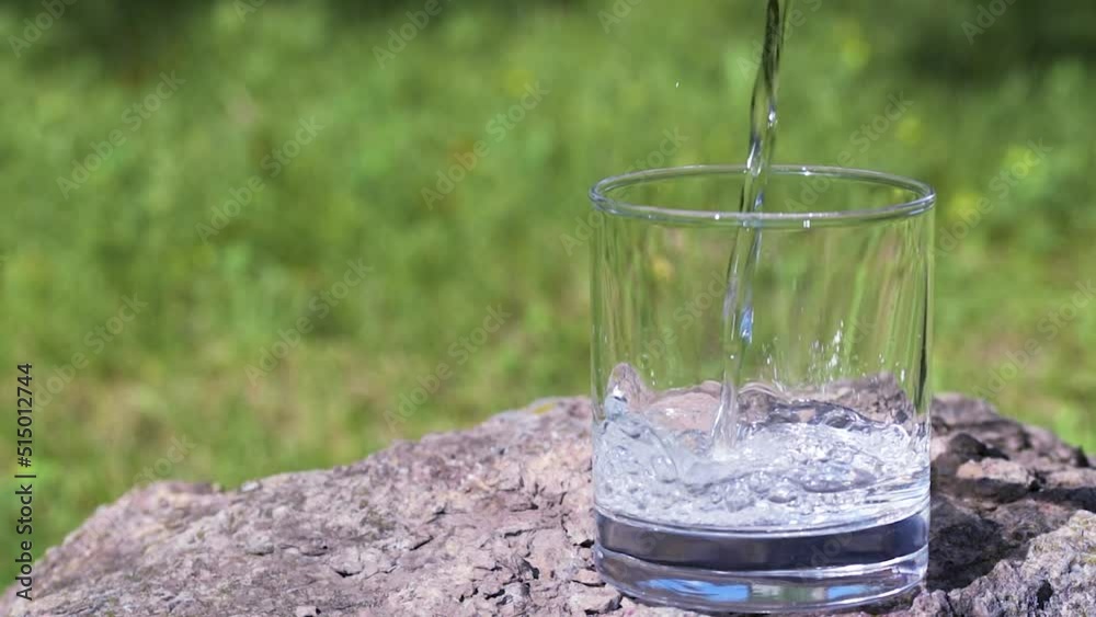 Fresh pure water pouring into a glass on a sunny summer day , closeup Fresh pure water pouring into a glass on a sunny summer day , closeup
