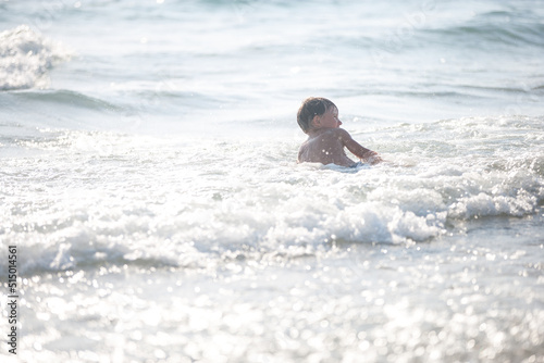 A little boy on the beach, playing with the waves, summer time. Concept of relaxation and a healthy lifestyle