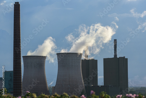 Chimney and cooling towers with steaming pollution of the steel production industry in Duisburg with blast furnaces, coke oven and power plant, industrial facility, dark blue sky, copy space
