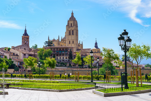 View of the world heritage city of Segovia with a nice park with flowers and grass.