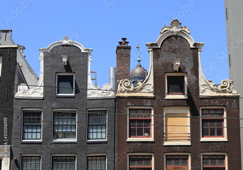 Amsterdam Nieuwezijds Voorburgwal Street Historic Brick House Facades with Neck Gables Against a Blue Sky Close Up, Netherlands. photo