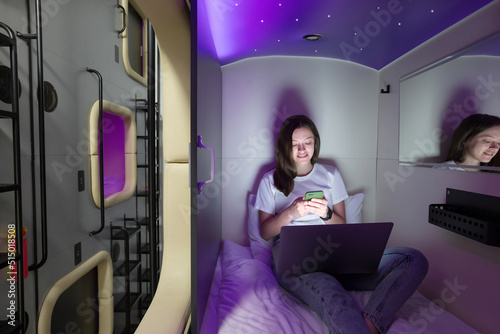 Young woman with gadgets in modern look capsule hotel photo