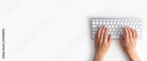 Female hands on the keyboard on a white background. Top view, flat lay. Banner