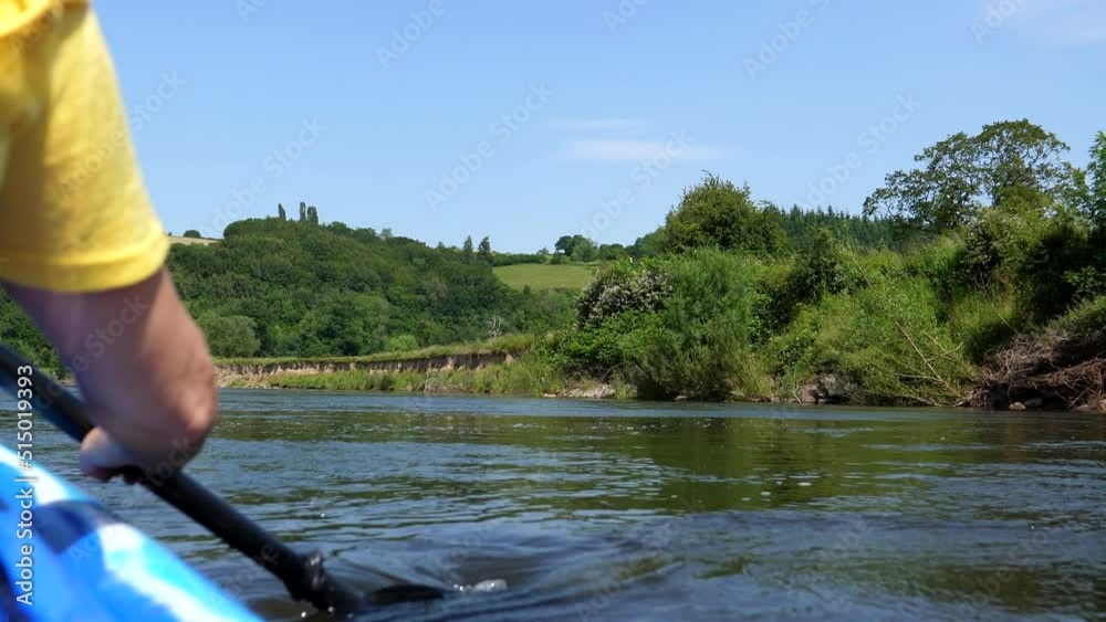 Woman paddling a double kayak on wide river Wye in South Wales, rear view of her right hand with an oar. Woman paddling a double kayak on wide river Wye in South Wales, rear view of her right hand with an oar.