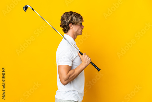 English man over isolated white background playing golf in lateral position