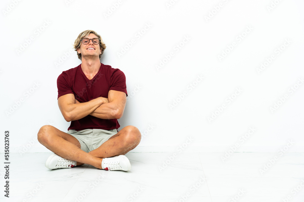 Young English man sitting on the floor with arms crossed and looking forward Young English man sitting on the floor with arms crossed and looking forward