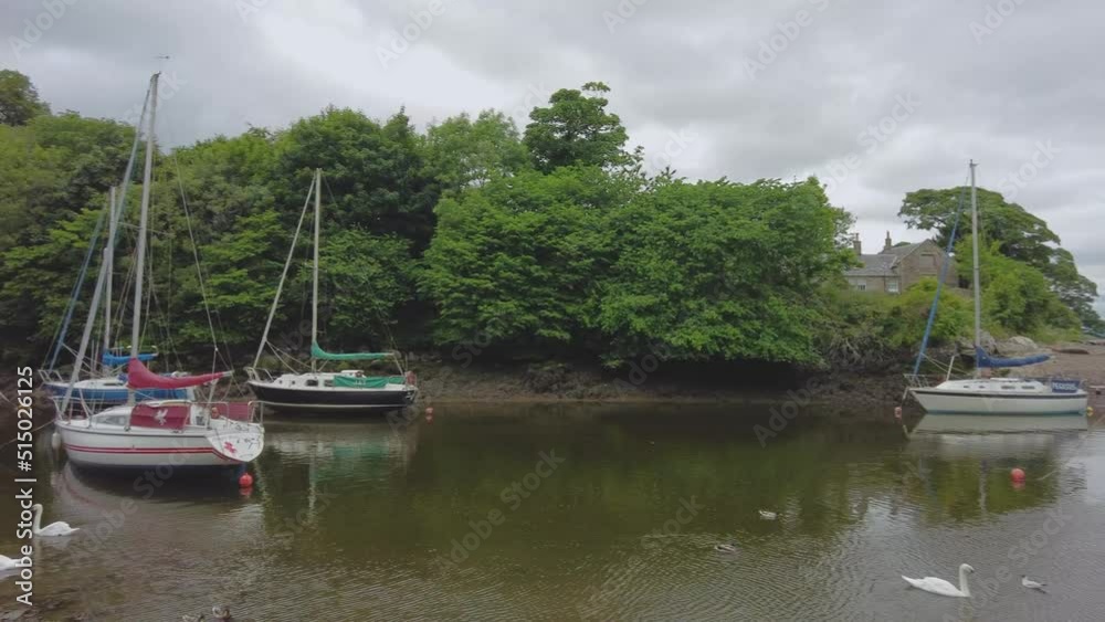 Cramond, Midlothian, Scotland – June 20 2022. A panning shot of sailboats, pleasure boats and yachts on the River Almond on a dull and overcast day Cramond, Midlothian, Scotland – June 20 2022. A panning shot of sailboats, pleasure boats and yachts on the River Almond on a dull and overcast day