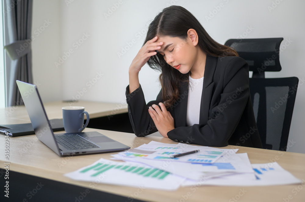 Stressed young business woman working on laptop with documents in modern office, workload concept Stressed young business woman working on laptop with documents in modern office, workload concept