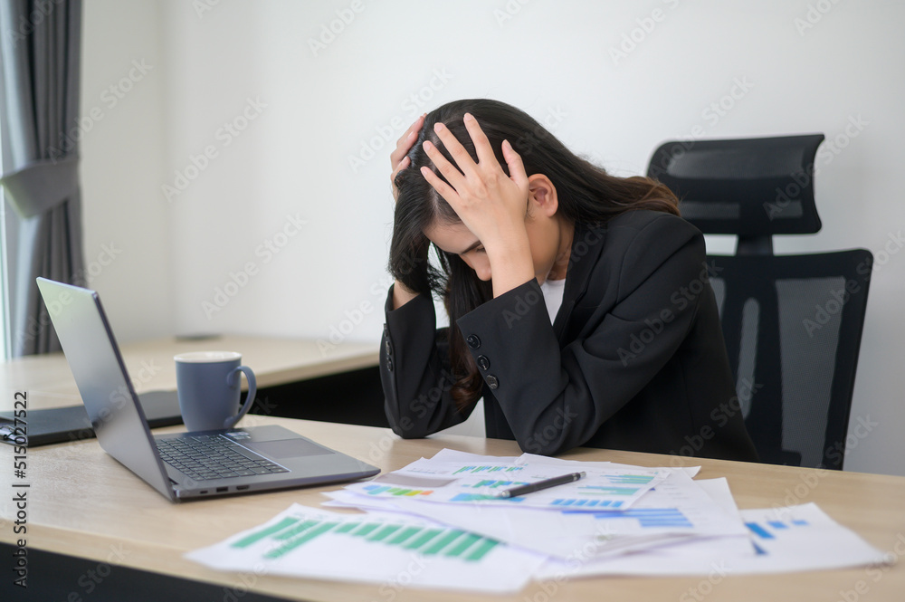 Stressed young business woman working on laptop with documents in modern office, workload concept Stressed young business woman working on laptop with documents in modern office, workload concept