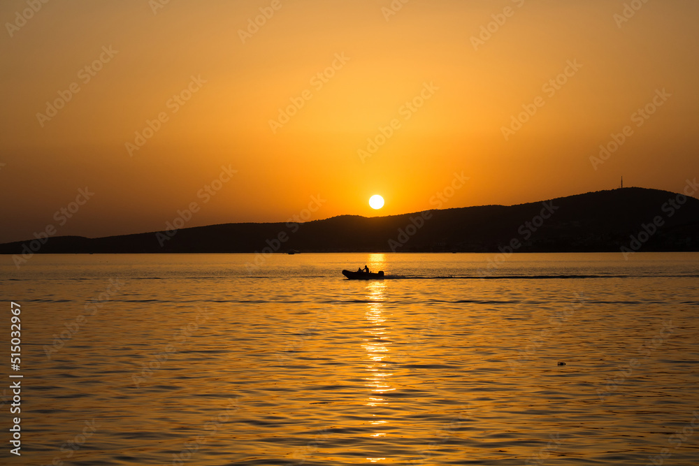 View of a small boat, Aegean sea and landscape at sunset captured in Ayvalik area of Turkey in summer.