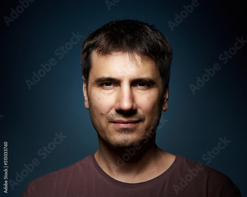 Portrait of a 42-year-old brunette man on a dark background with bright illumination