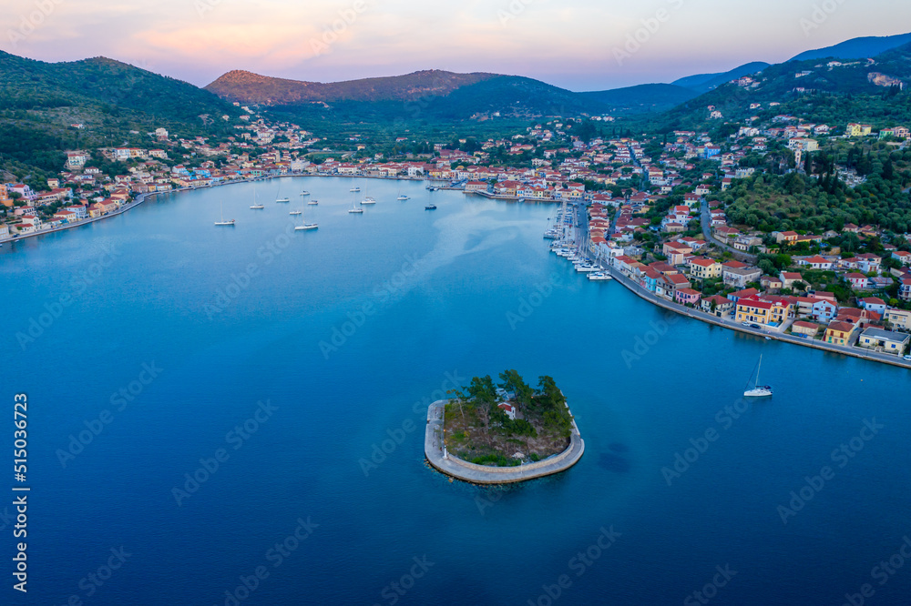 Vathy harbor with sailboats and catamarans anchored on the shore of the village of Ithaca Greece. Small marina Limani Vathy with a small island at the entrance. Sunset over the harbour. Beautiful Sea 
