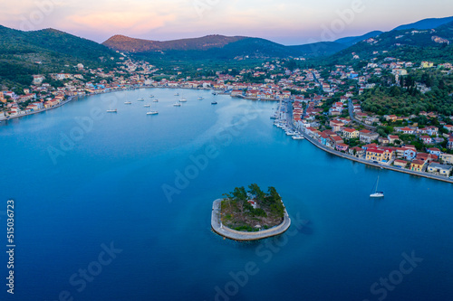Vathy harbor with sailboats and catamarans anchored on the shore of the village of Ithaca Greece. Small marina Limani Vathy with a small island at the entrance. Sunset over the harbour. Beautiful Sea 