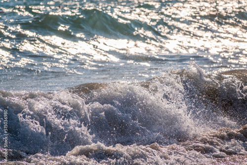 Splashes of water and foam against the sea on a sunny summer day