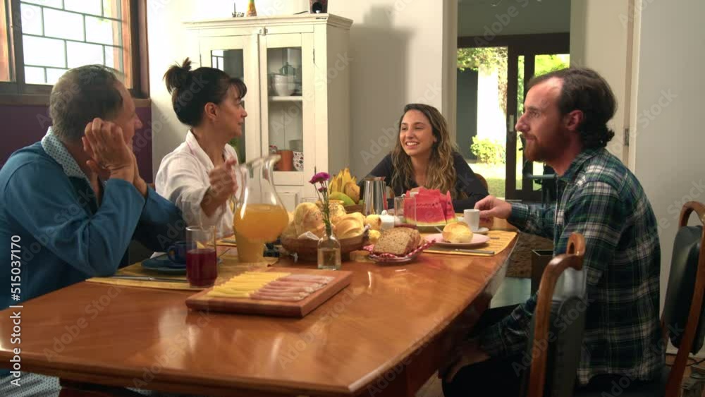Family sitting at breakfast table in the morning. Older parents with adult son and daughter together Family sitting at breakfast table in the morning. Older parents with adult son and daughter together