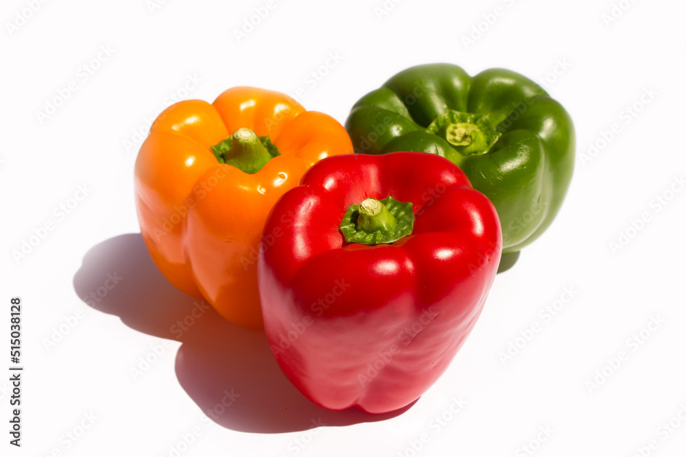 three different colored peppers: red, green and yellow peppers lie on a white background three different colored peppers: red, green and yellow peppers lie on a white background