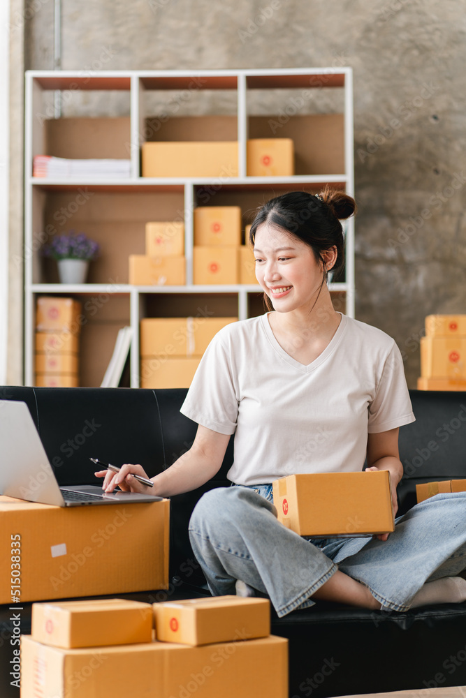 Portrait of a small business startup, SME owner, female entrepreneur, working, unboxing, checking orders online. To prepare to pack boxes for sale to SME customers online business ideas