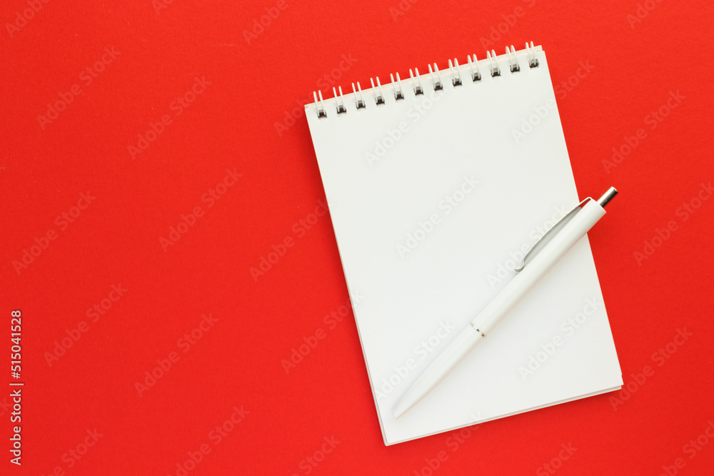 Blank notepad on spirals and pen on bright red background. Sketchbook for drawing or notes. Art and hobby concept. Top view, flay lay with copy space. Blank notepad on spirals and pen on bright red background. Sketchbook for drawing or notes. Art and hobby concept. Top view, flay lay with copy space.