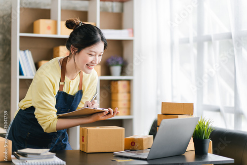 Portrait of a small business startup, SME owner, female entrepreneur, working, unboxing, checking orders online. To prepare to pack boxes for sale to SME customers online business ideas