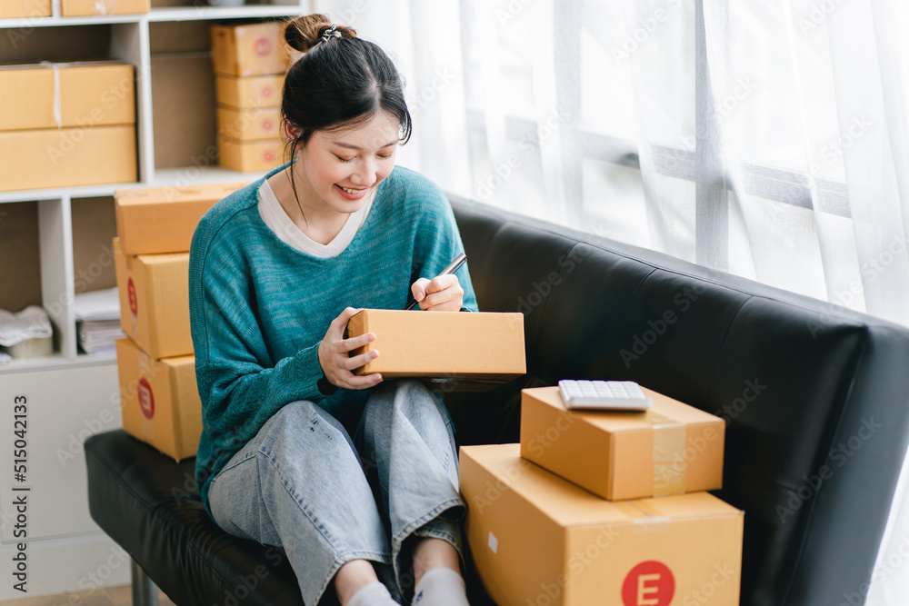 Portrait of a small business startup, SME owner, female entrepreneur, working, unboxing, checking orders online. To prepare to pack boxes for sale to SME customers online business ideas