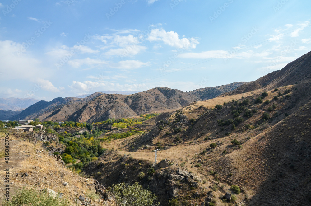 Autumn landscape of gentle slopes of mountainous terrain covered with trees and dry grass. Caucasus Mountains, Armenia