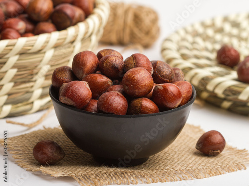 hazelnut covered served in a bowl isolated on napkin side view of nuts on grey background photo