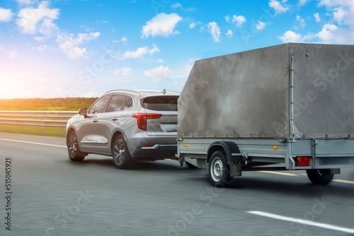 Foto Car with a trailer covered with an awning is driving along the highway in the sky clouds and sunset
