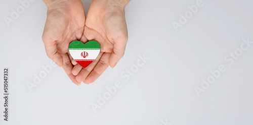 The national flag of Iran of arms in female hands. Flat lay, copy space.