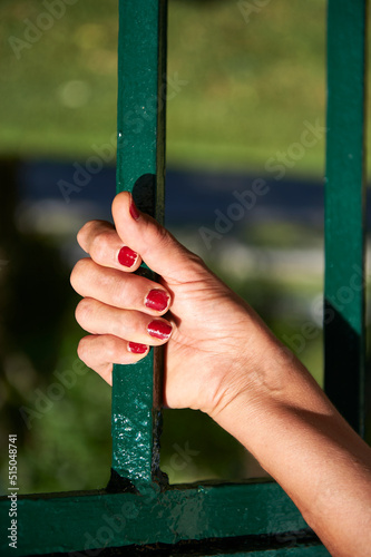 hand gripping a green steel bar with weathered crimson nails