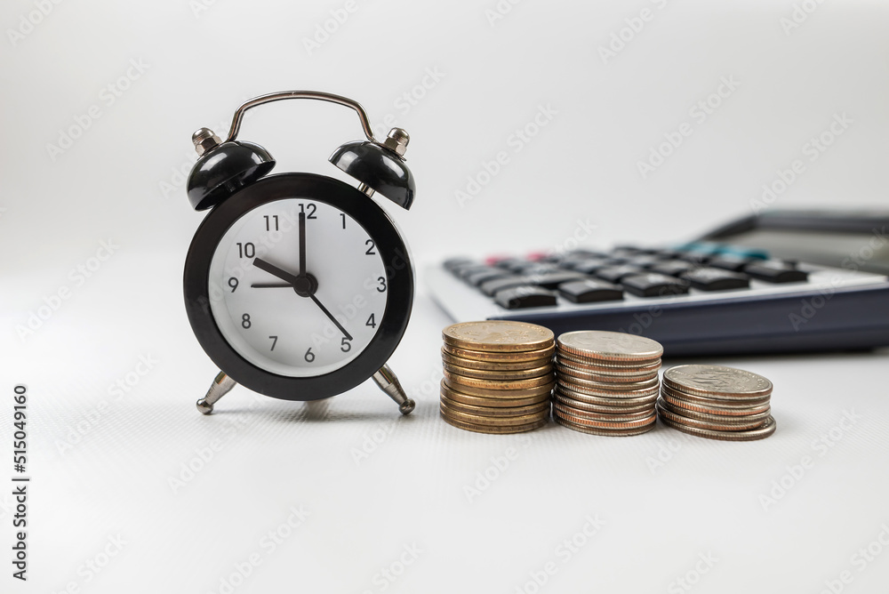 stacks of coins with alarm clock and calculator on white. stacks of coins with alarm clock and calculator on white.