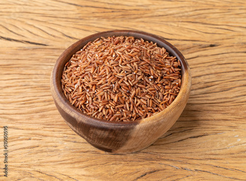 Raw red whole rice in a bowl over wooden table
