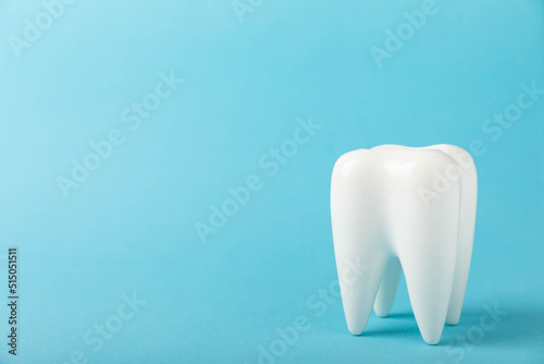 White tooth model on a blue wooden background. The concept of dental hygiene. Prevention of plaque and gum disease.MOCKUP