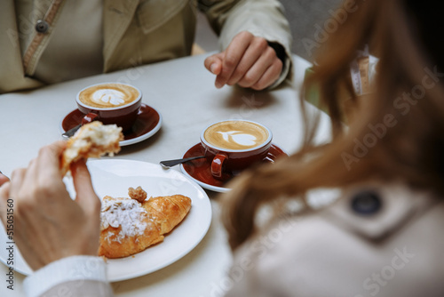 Couple in love drinking coffee and eating croissants at a table on the outdoor terrace of a cafe