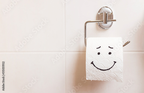 a roll of toilet paper with a happy face hanging on a white wall in the bathroom photo