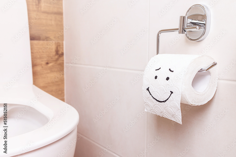 Fototapeta premium a roll of toilet paper with a happy face hanging on a white wall in the bathroom