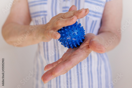 elderly woman squeezes a prickly ball in her hands, self-massage with parkinson