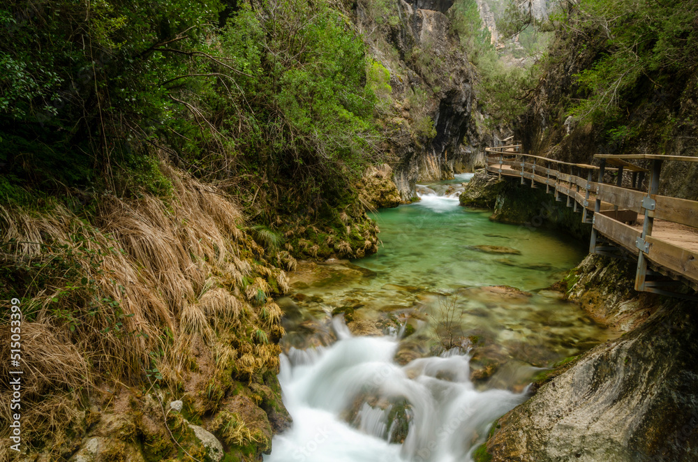 wooden walkway over the borosa river in the Sierra de Segura (Spain) without any people, on a cloudy autumn day. The river water with silk effect wooden walkway over the borosa river in the Sierra de Segura (Spain) without any people, on a cloudy autumn day. The river water with silk effect