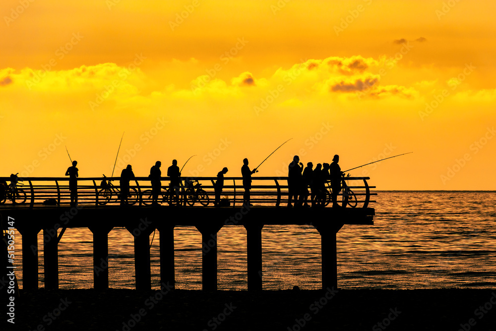 fishermen crowd silhouette on sunset pier