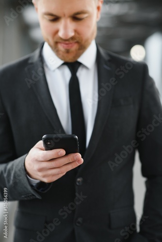 Businessman using smartphone in covered walkway.