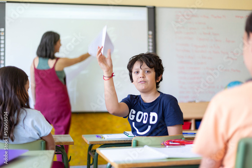 Caucasian child playing in class while teacher is explaining the lesson. Primary education, back to school.