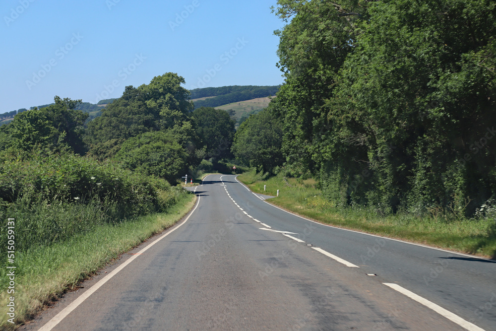 Downhill on an empty road in Somerset, England. Lush green rolling hills can be seen in the background